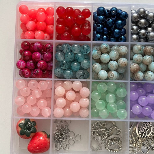 Close-up of the beading kit compartments with pastel beads and silver charms - Beads by Nia