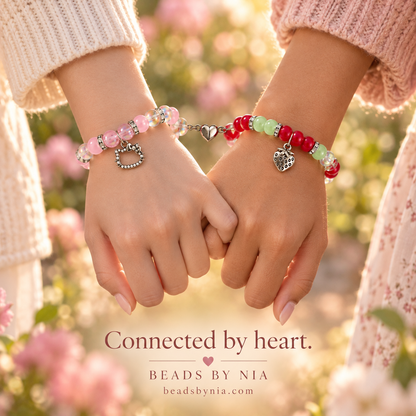 Two wrists connected by heart clasps in Hello Kitty and Strawberry Shortcake bracelets